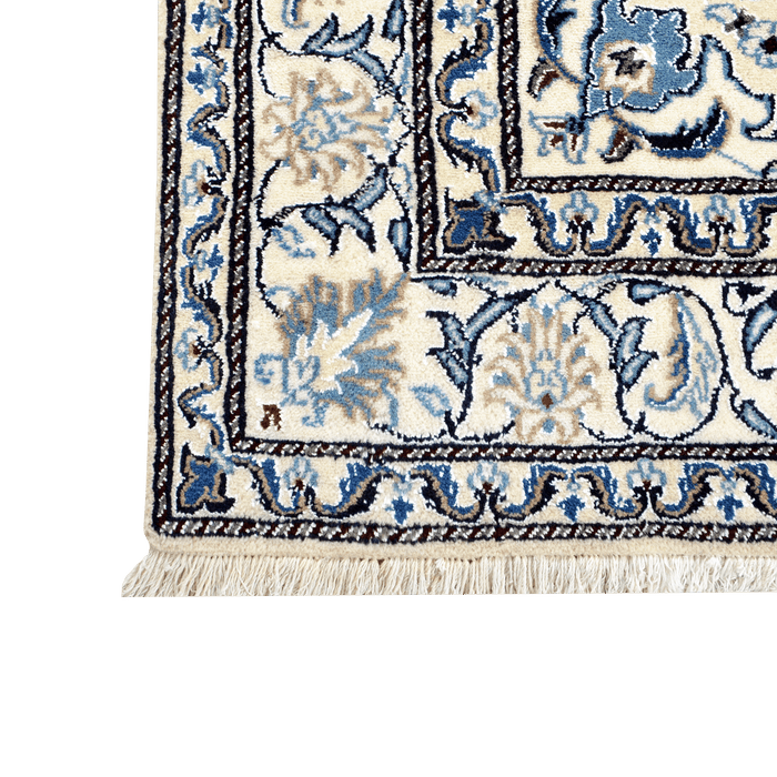 Cam Rugs: A corner of a cream base handmade Nain wool area rug, with accented blue details of floral motif designs.