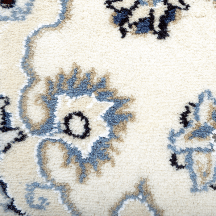 Cam Rugs: A detail of a cream base handmade Nain wool area rug, with accented blue details of floral motif designs.