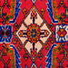 The center of a red handmade Kashkoli wool area rug, with a traditional geometric motif design. 