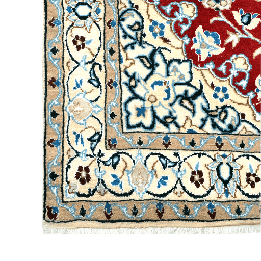 Cam Rugs: A corner of a cream base handmade Nain wool area rug, with accented red details of floral motif designs. 