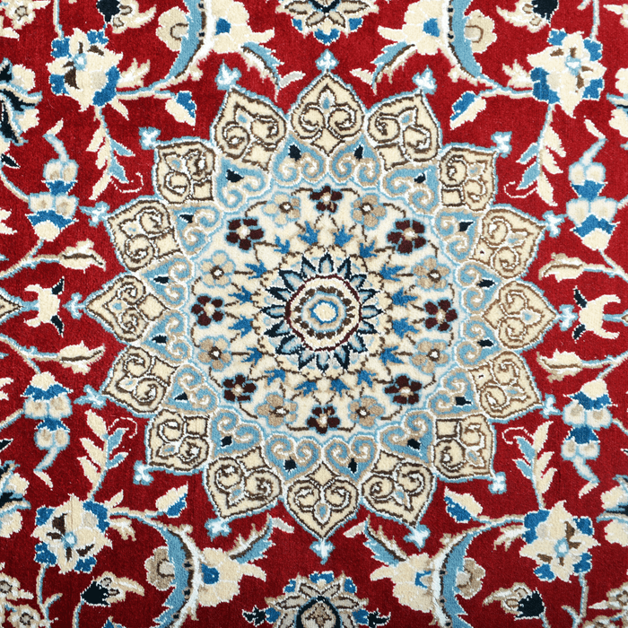 Cam Rugs: The center medallion of a cream base handmade Nain wool area rug, with accented red details of floral motif designs. 