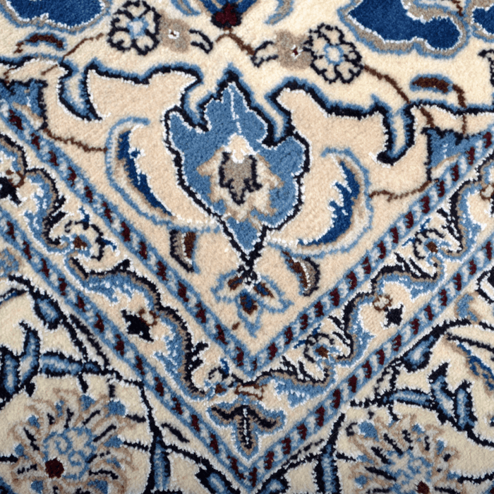 Cam Rugs: A detail of a cream base handmade Nain wool area rug, with accented blue details of floral motif designs. 
