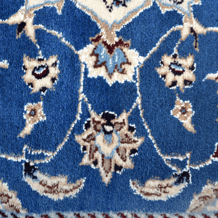 Cam Rugs: A detail of a cream base handmade Nain wool area rug, with accented blue details of floral motif designs. 