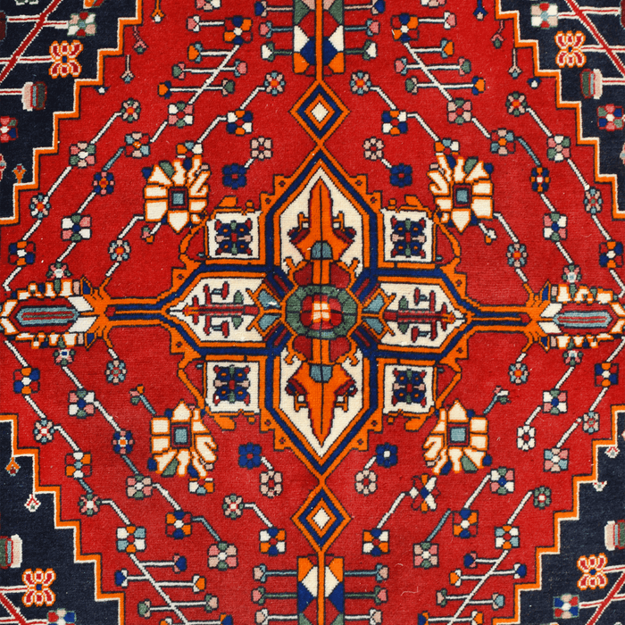 The center of a red handmade Kashkoli wool area rug, with a traditional geometric motif design. 