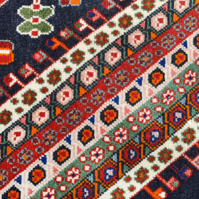 A close-up detail of a red handmade Kashkoli wool area rug, with a traditional geometric motif design. 