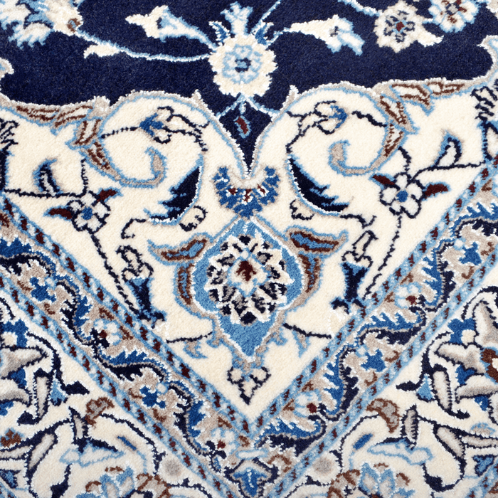 Cam Rugs: A close-up detail of a cream and blue Nain wool area rug, with a traditional floral motif design.