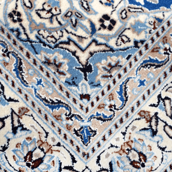 Cam Rugs: A close-up detail of a cream and blue Nain wool area rug, with a traditional floral motif design.