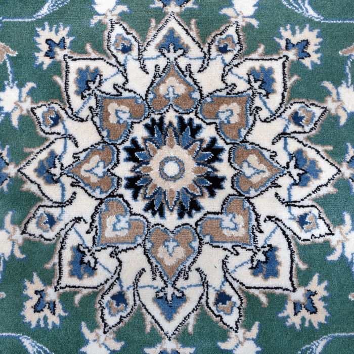 The center of a cream and green Nain wool area rug, with a traditional floral motif design.
