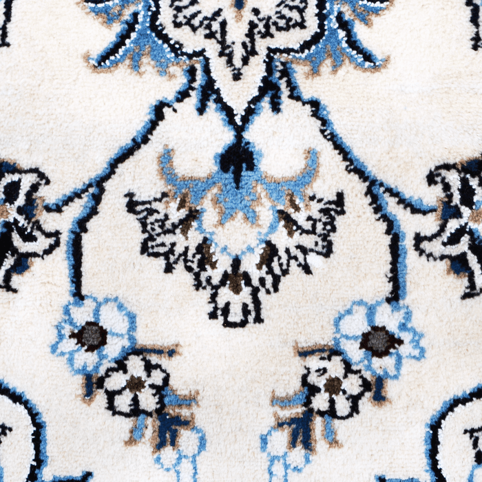 A detail of a cream handmade Nain wool area rug, with a traditional floral motif design.