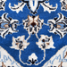 A close-up detail of a cream and blue Nain wool area rug, with a traditional floral motif design.