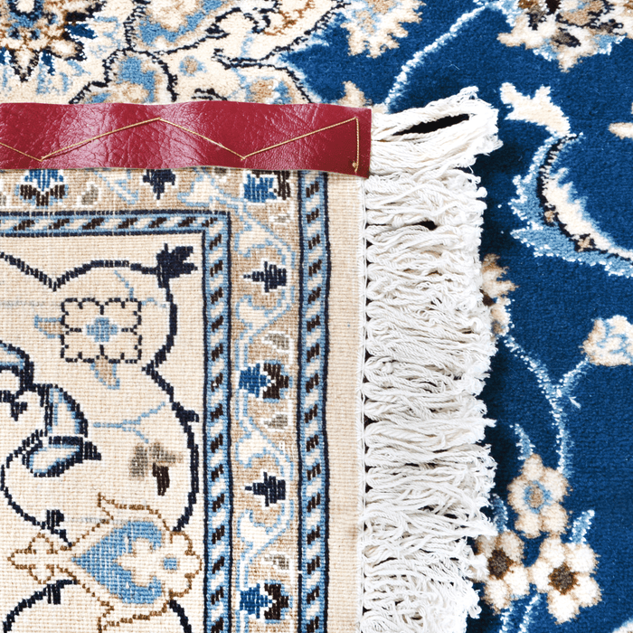The back of a cream and blue Nain wool area rug, with a traditional floral motif design.