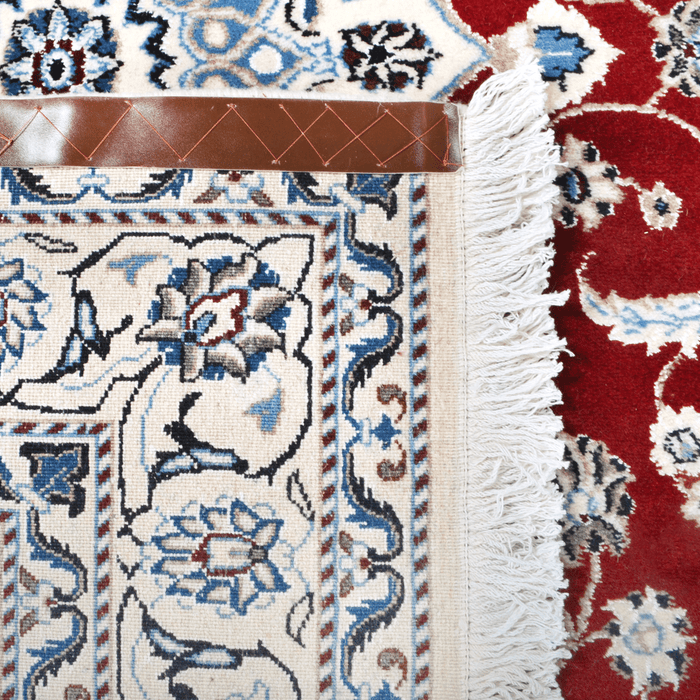 The back of a cream and red Nain wool area rug, with a traditional floral motif design.