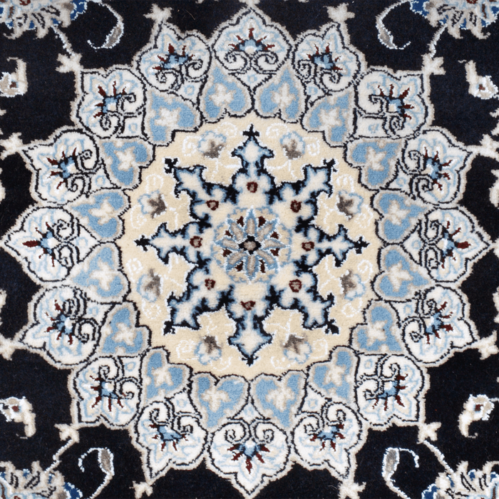 The center of a cream and black Nain wool area rug, with a traditional floral motif design.