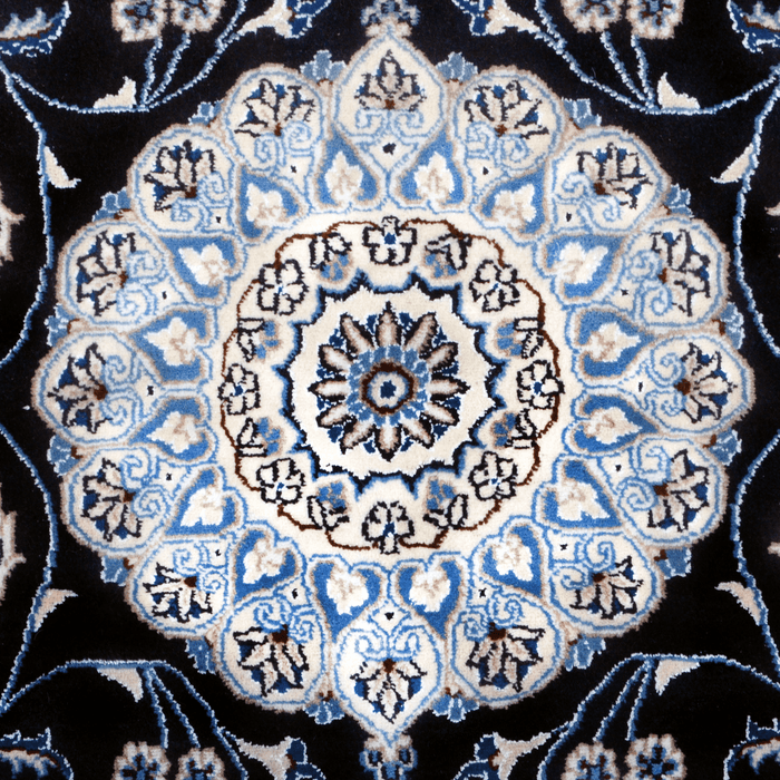 The center of a cream and blue Nain wool area rug, with a traditional floral motif design.