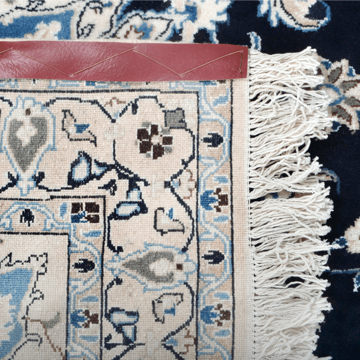 The back of a cream and blue Nain wool area rug, with a traditional floral motif design.