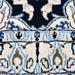 A close-up detail of a cream and blue Nain wool area rug, with a traditional floral motif design.