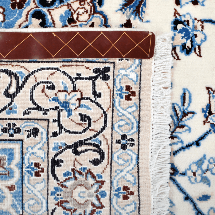 Cam Rugs: The back of a cream and blue Nain wool area rug, with a traditional floral motif design.