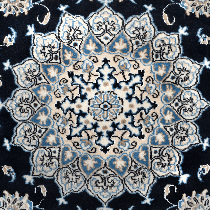 The center of a cream and blue Nain wool area rug, with a traditional floral motif design.
