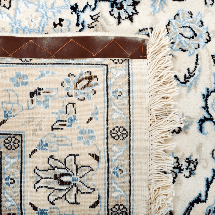 The back of a cream Nain wool area rug, with a traditional floral motif design.