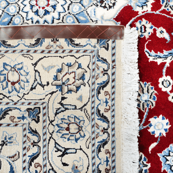The back of a cream and red Nain wool area rug, with a traditional floral motif design.