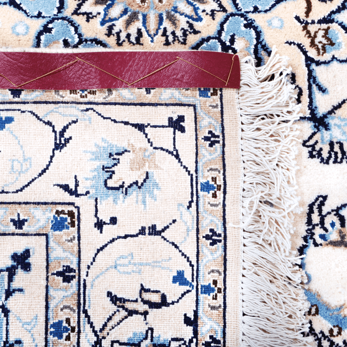 The back of a cream Nain wool area rug, with a traditional floral motif design.