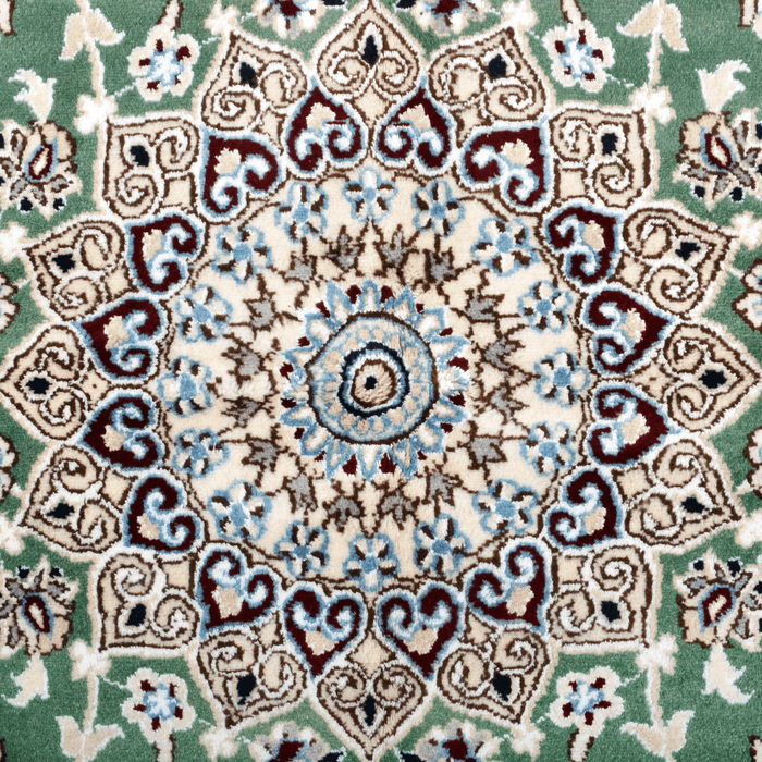 Cam Rugs: The center medallion of a cream base handmade Nain wool area rug, with accented green details of floral motif designs.