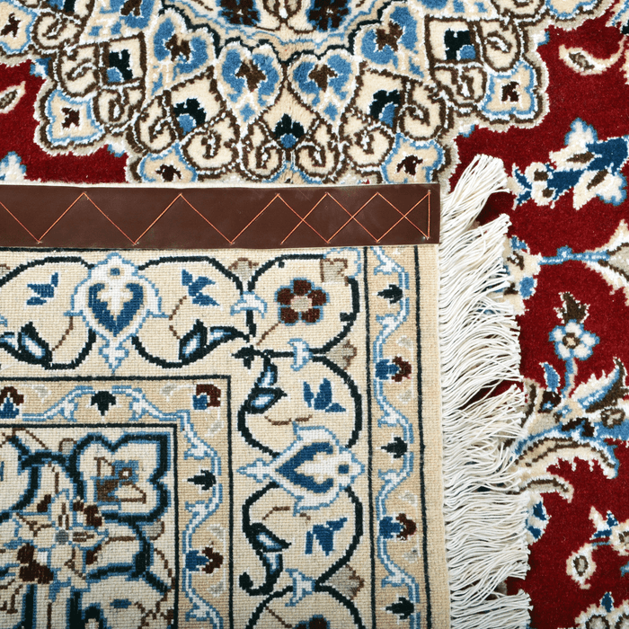 Cam Rugs: The back of a cream base handmade Nain wool area rug, with accented red details of floral motif designs. 