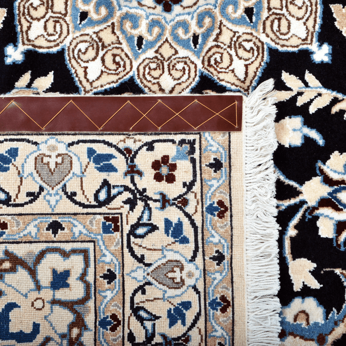 Cam Rugs: The back of a cream base handmade Nain wool area rug, with accented black details of floral motif designs. 