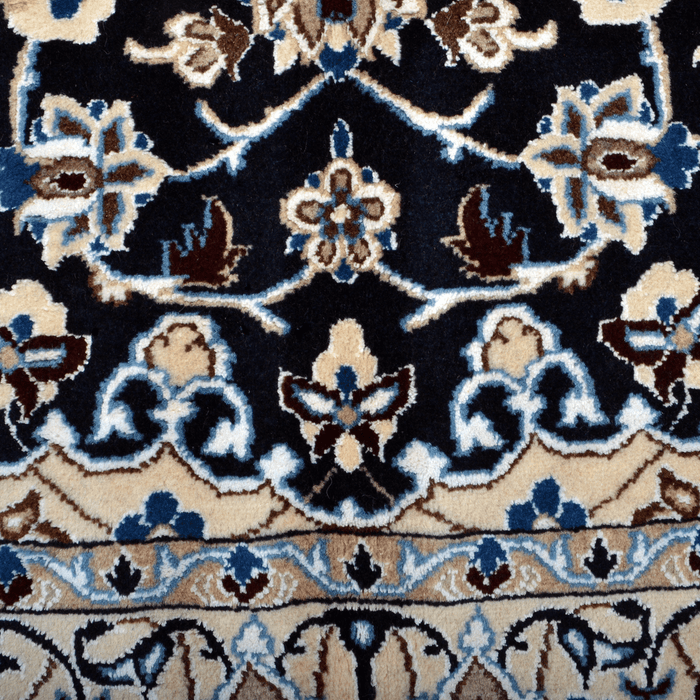 Cam Rugs: A detail of a cream base handmade Nain wool area rug, with accented black details of floral motif designs. 