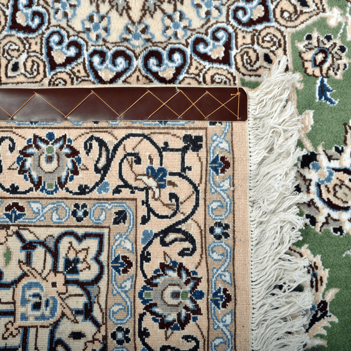 Cam Rugs: The back of a cream base handmade Nain wool area rug, with accented green details of floral motif designs.