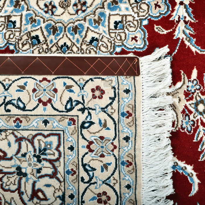 Cam Rugs: The back of a cream base handmade Nain wool area rug, with accented red details of floral motif designs. 