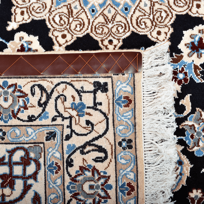 Cam Rugs: The back of a cream base handmade Nain wool area rug, with accented blue details of floral motif designs.