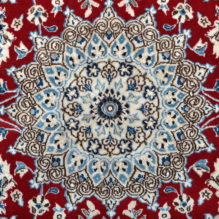 The center of a cream and red Nain wool area rug, with a traditional floral motif design.