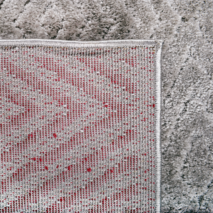 The back of a grey textured area rug with embossed geometric diamond designs.