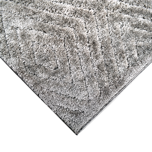 A corner of a grey textured area rug with embossed geometric diamond designs.