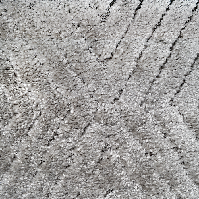 A detail of a grey textured area rug with embossed geometric diamond designs.