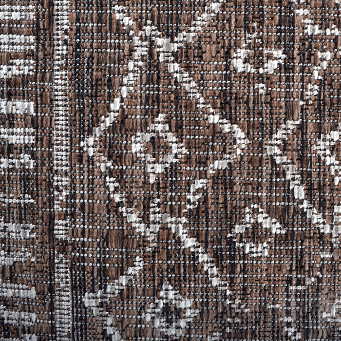 A detail of a brown flat weave outdoor rug with geometric designs.