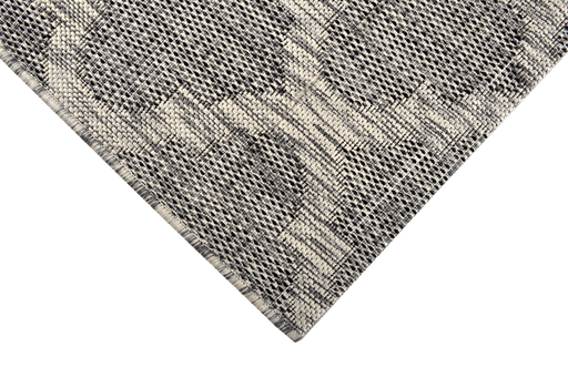 A corner of a grey flat weave outdoor rug with modern geometric designs.