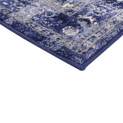 A corner of a purple textured area rug with distressed traditional floral designs.
