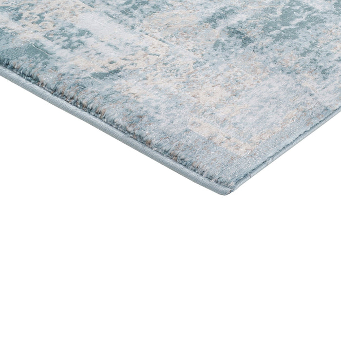 A corner of a blue textured area rug with distressed traditional floral motif designs,