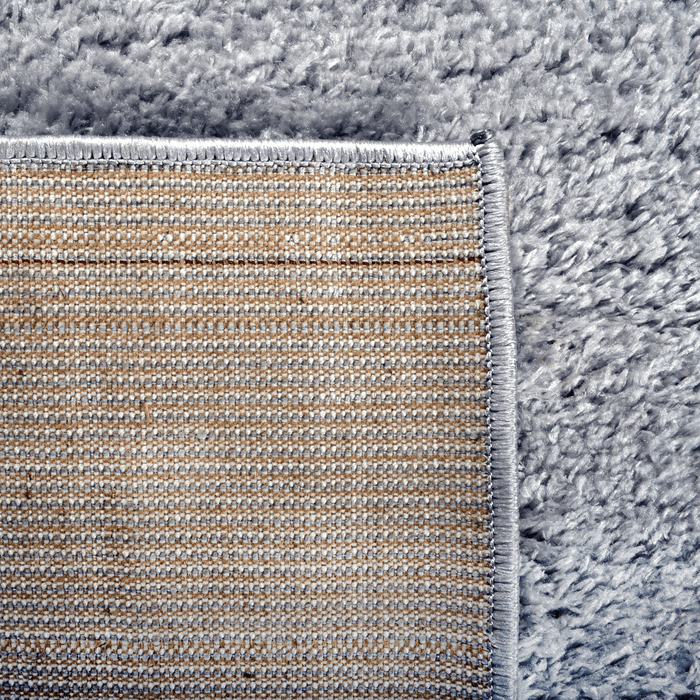 The back of a solid grey shag area rug.