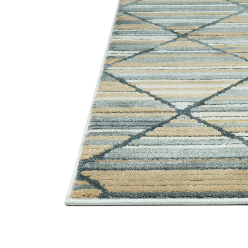 A corner of a blue, beige and cream area rug with triangle and striped geometric designs.