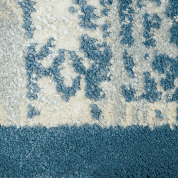 A close-up detail of a blue and cream area rug with distressed traditional floral motif designs.