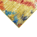 A corner of a yellow area rug with multi-coloured geometric diamond designs.
