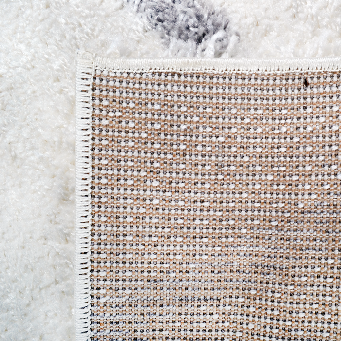 The back of a cream shag area rug, with diamond geometric designs.