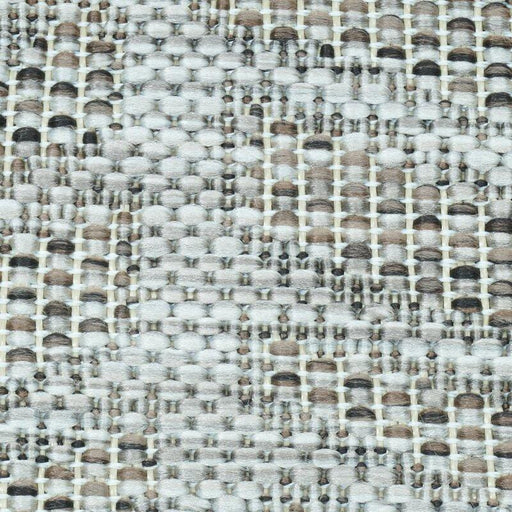 A detail of a beige flat weave outdoor rug with wavy geometric designs.