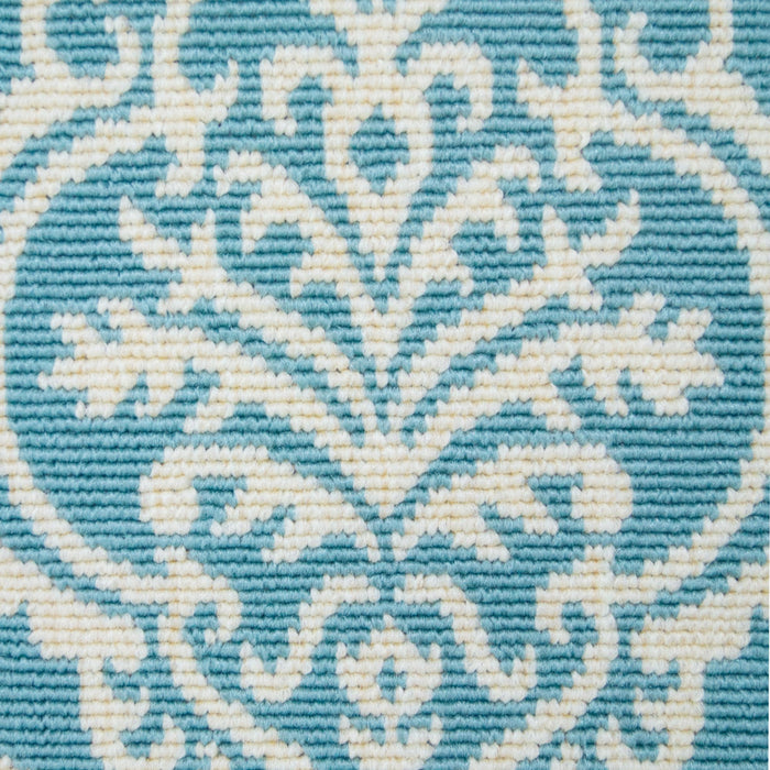 A detail of a green area rug, with floral damask designs.