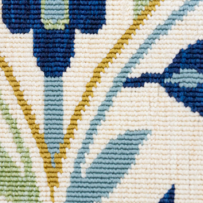 A detail of a cream area rug, with blue, green, and yellow floral damask designs.