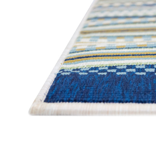 A corner of a cream area rug, with blue, green and yellow stripes.
