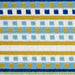 A detail of a cream area rug, with blue, green and yellow stripes.